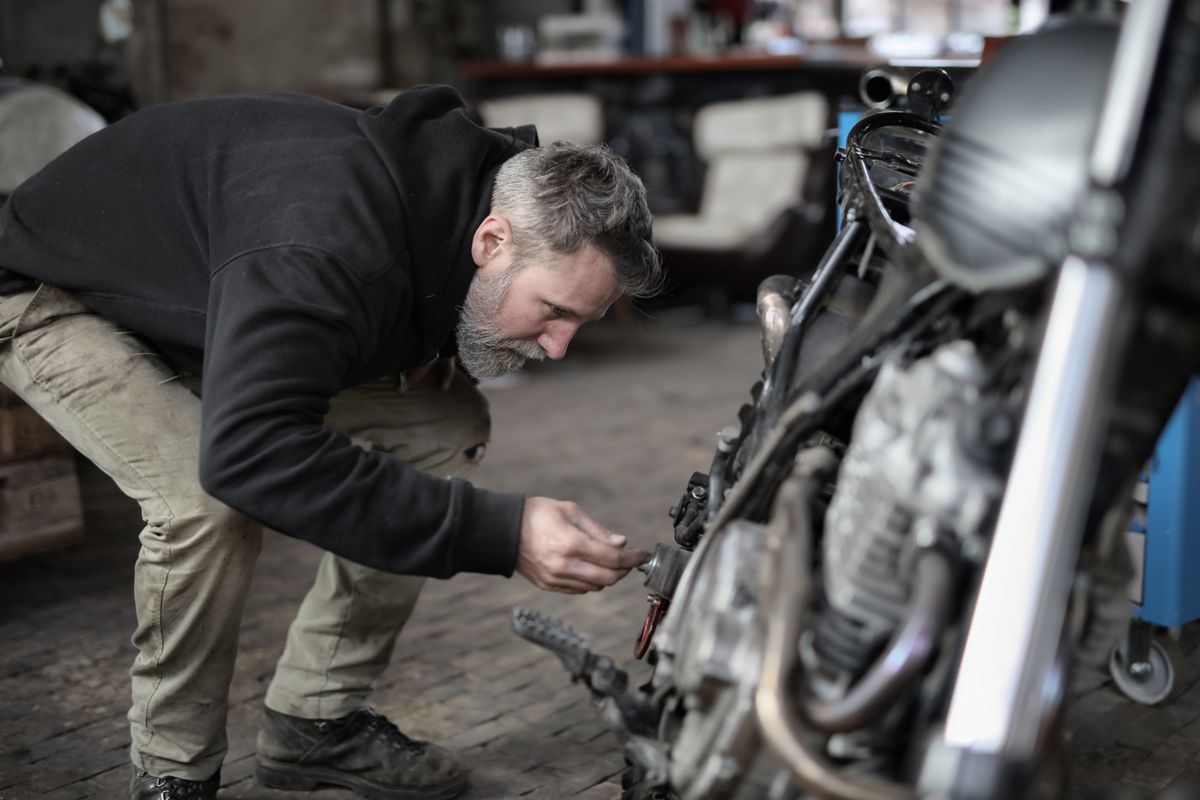 Motosikletin parçalarını yakından kontrol eden servis ustası